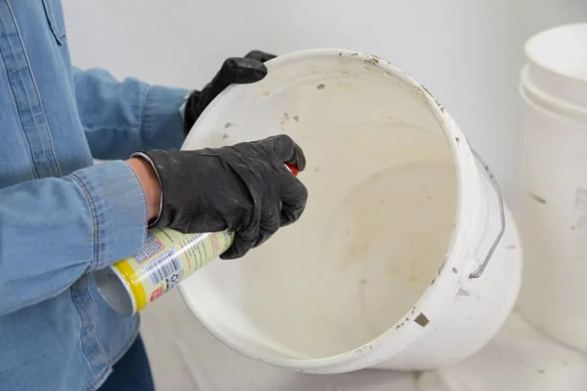 Rociar un balde de plástico con aceite en aerosol