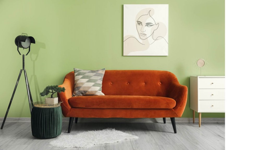 Salón con sofá naranja y pared verde.