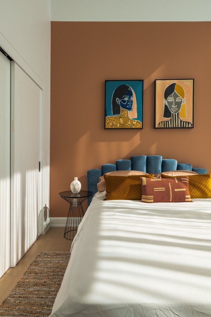 Dormitorio con pared marrón y cabecero azul.