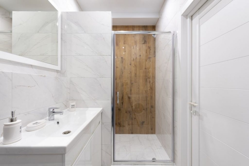 ideas modernas de renovación de baño con lavabo rectangular blanco y revestimientos de ducha con efecto de madera.