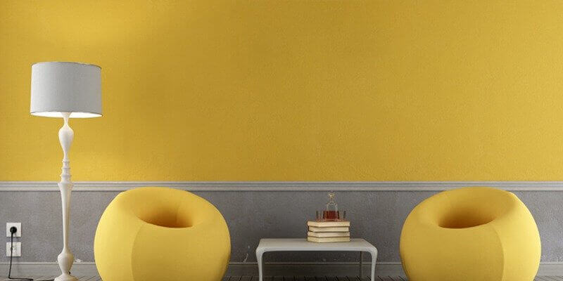 Iluminando la pared amarilla pantone con sillones amarillos y lámpara gris