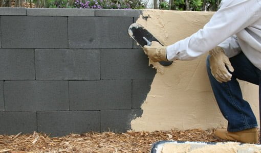 Aplicar cemento de unión de superficies a una pared de bloques de hormigón apilados en seco