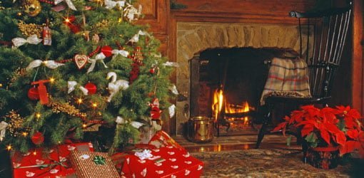 Árbol de Navidad con regalos junto a la chimenea.
